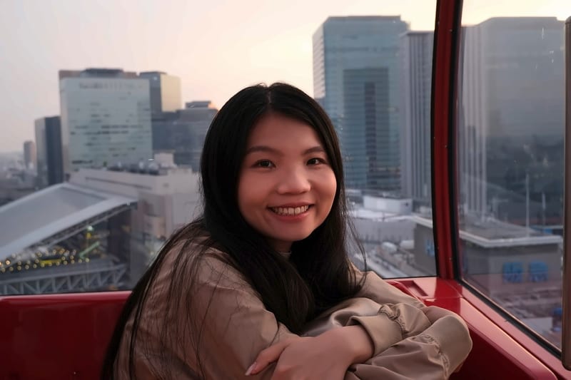 黄昏的摩天轮车厢里，一名女子倚着窗边微笑